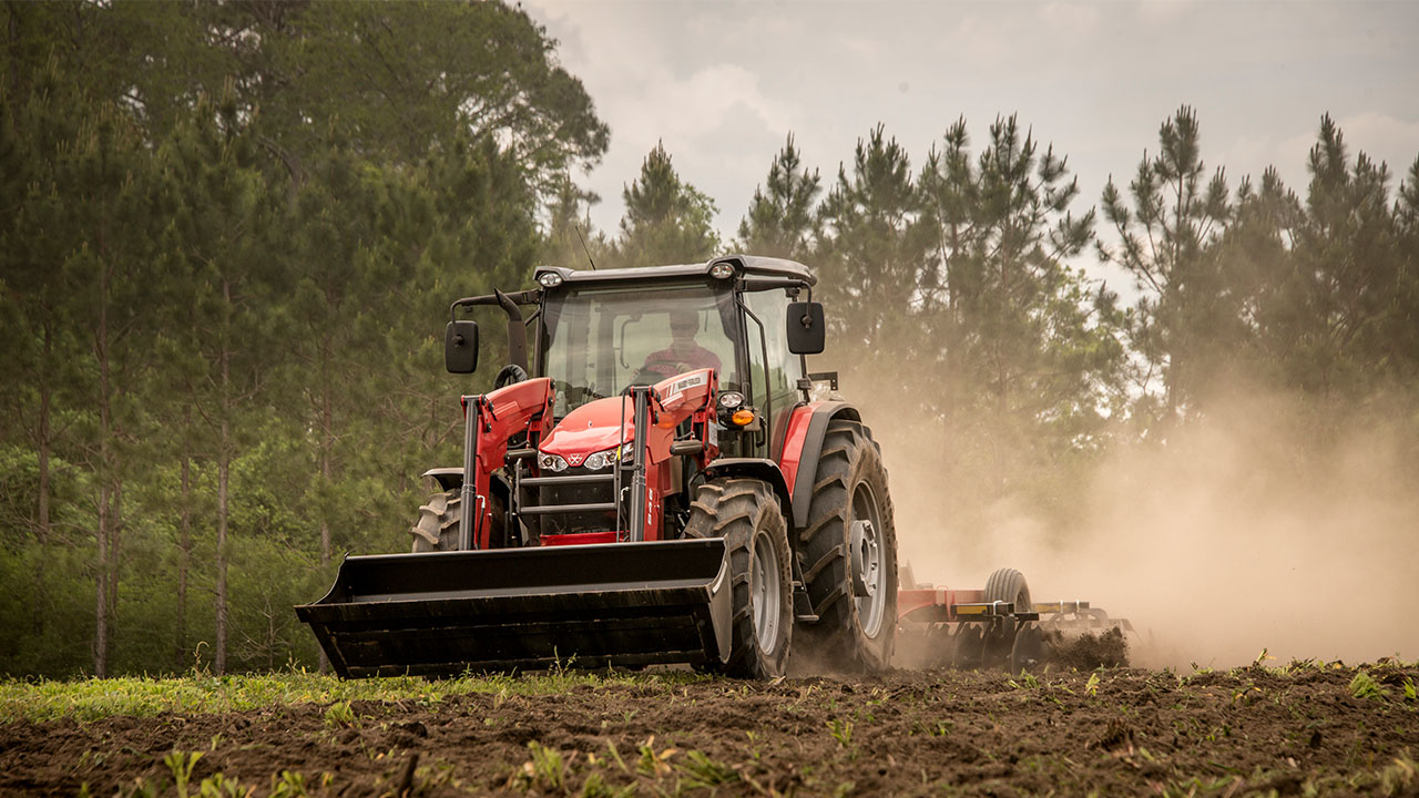 Massey Ferguson 6700 Series tractor with front loader working a dusty field, built for power, performance, and tough agricultural tasks.