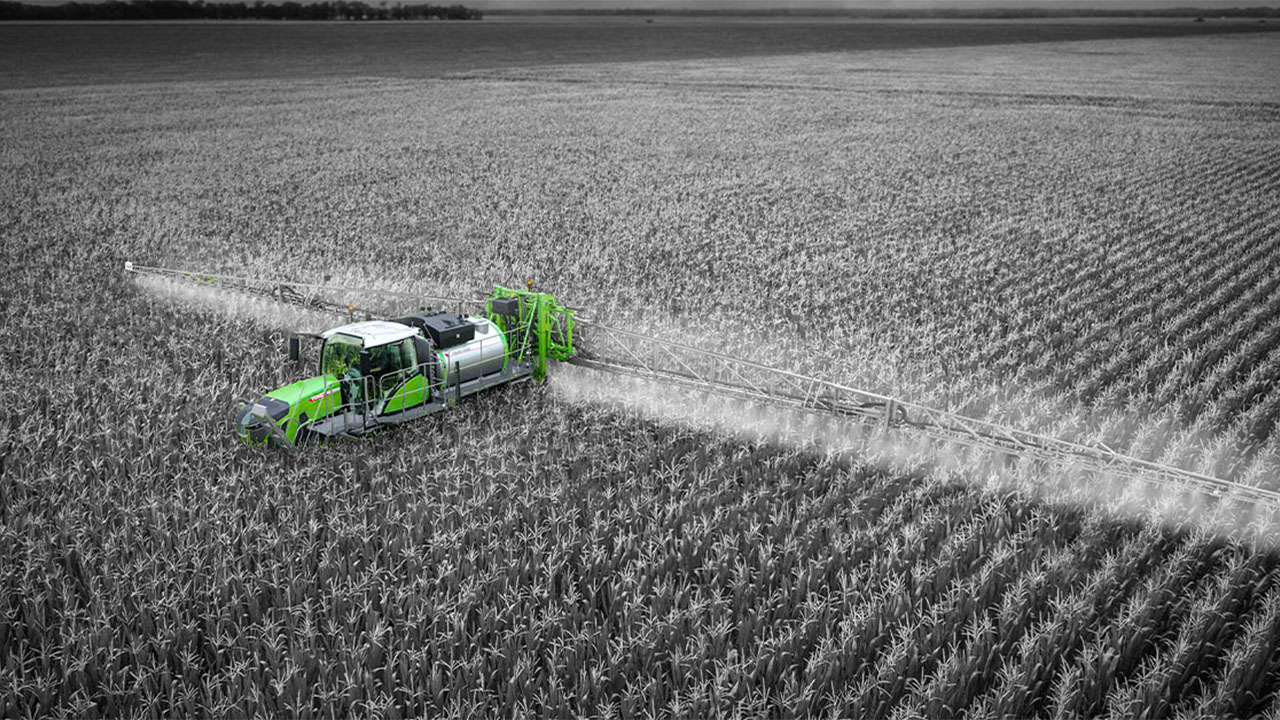 Fendt Rogator sprayer applying crop treatment in a cornfield, precision agriculture, AGCO technology, aerial view.