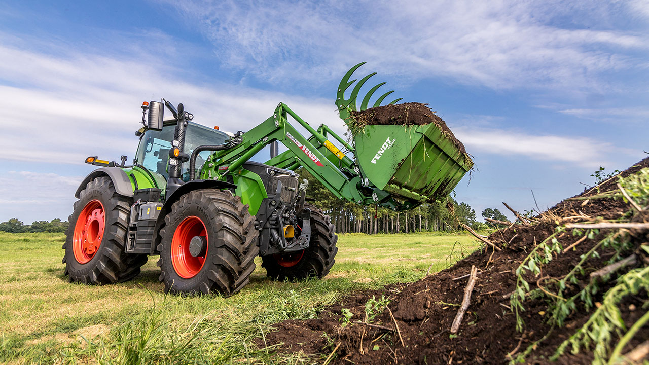 Fendt 700 Vario Gen7 moving soil and brush on a field, showcasing strength and versatility.