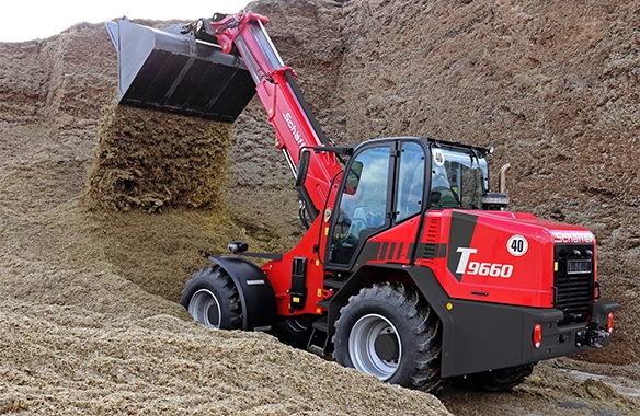 Thumbnail for Schäffer 9660 T telescopic wheel loader operating deep inside a silage bunker, lifting with a full bucket load.