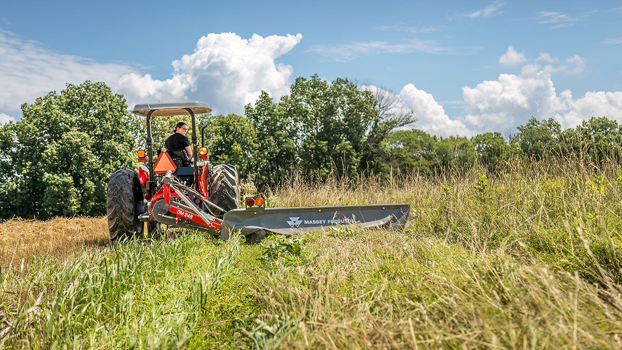 Massey Ferguson tractor with MF DM Series Disc Mower cutting a dense grass field, built for clean, efficient mowing.