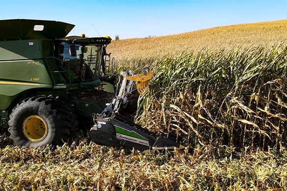 John Deere S780 combine harvesting tall corn using a Geringhoff Freedom Series corn head in gently rolling terrain.