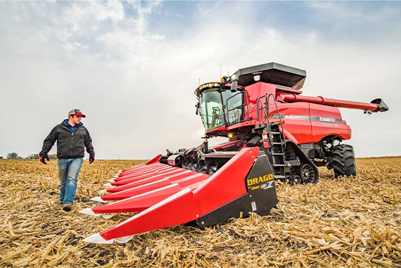 Farmer standing next to a Case IH 8240 combine equipped with a Drago Series II corn head, ready for high-efficiency corn harvest in a stubble field.