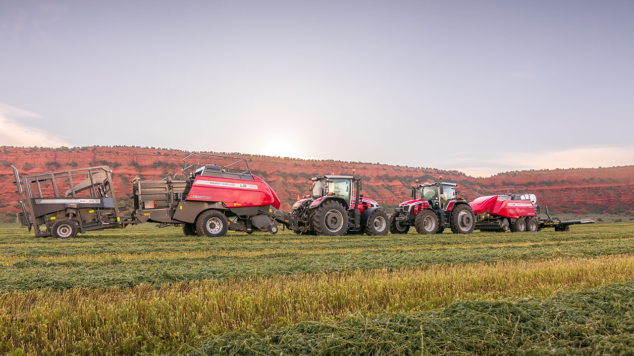 Hesston by Massey Ferguson LB2200 Series balers working in tandem with Massey Ferguson tractors in a field at sunset.