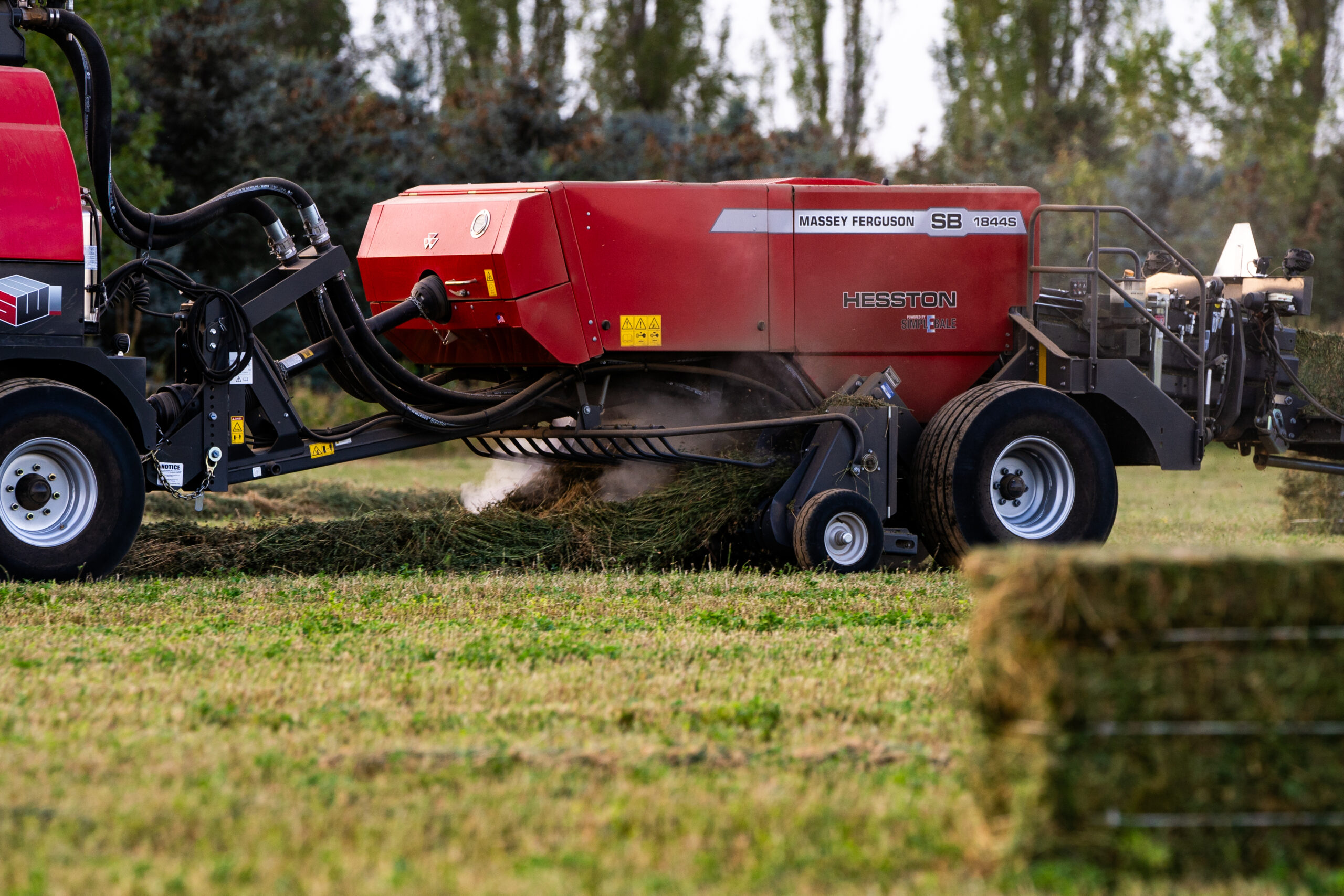 Hesston by Massey Ferguson SB 1844S large square baler collecting hay with SimplEbale system in green field.