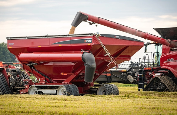 Thumbnail for Brandt 1520XT grain cart receiving harvested grain from a combine, featuring high-capacity design and efficient unloading system in a field setting.