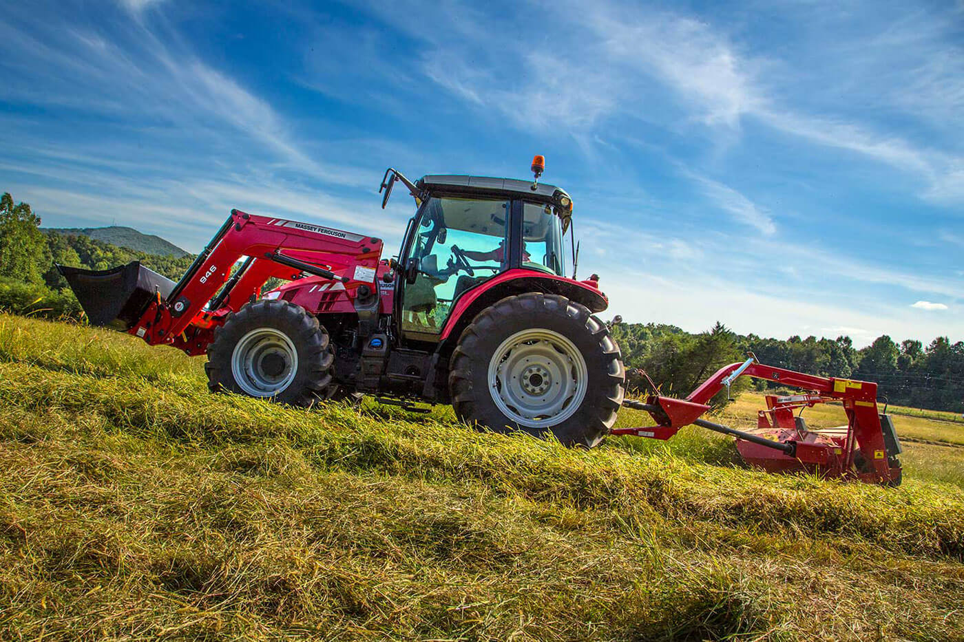 MF 1300 Series Mower Conditioner attached to a Massey Ferguson tractor cutting hay in a sunny, open field.