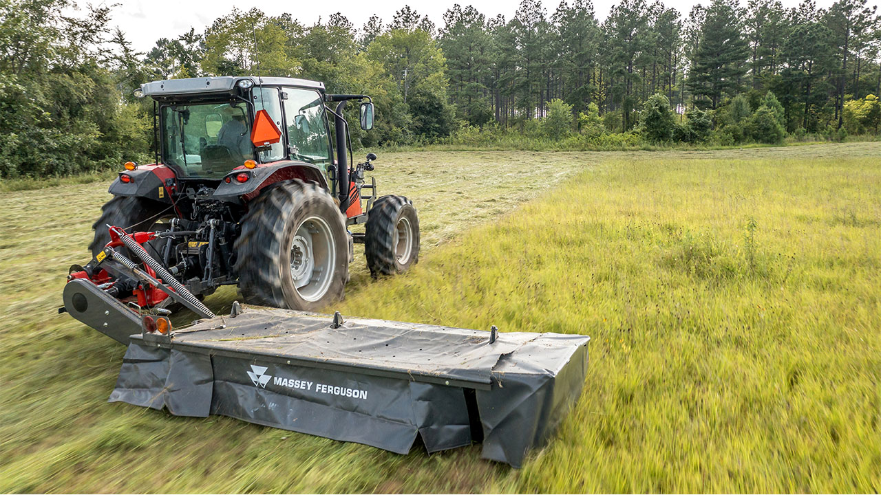 Massey Ferguson tractor with MF DM Series front-mounted mower cutting tall grass, built for visibility and precision in tight spaces.