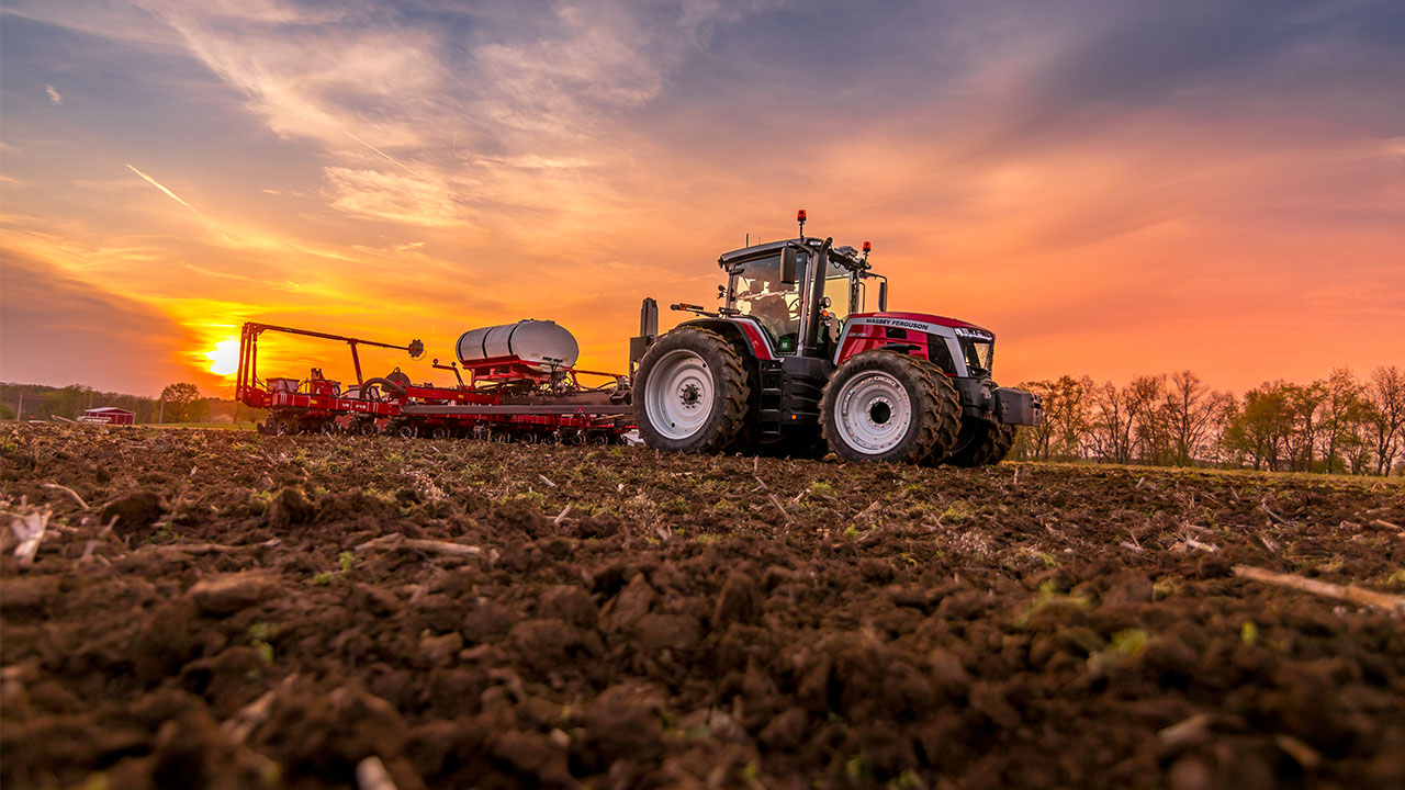 Massey Ferguson planter in action at sunset, planting rows across a field with precision AGCO farming technology.