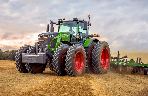 Fendt 900 Vario high-horsepower tractor with dual rear wheels operating in a field with tillage equipment during a cloudy day.