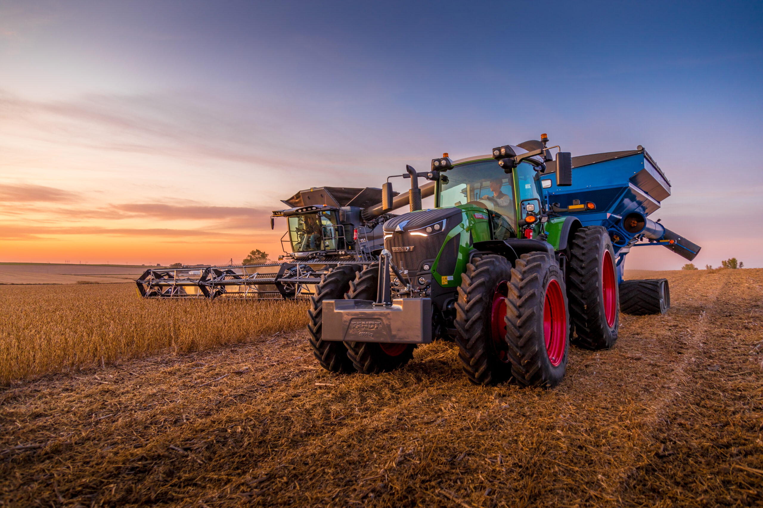 Fendt 900 Vario tractor with grain cart and Fendt IDEAL combine harvesting soybeans at sunset near Sioux City, Iowa.