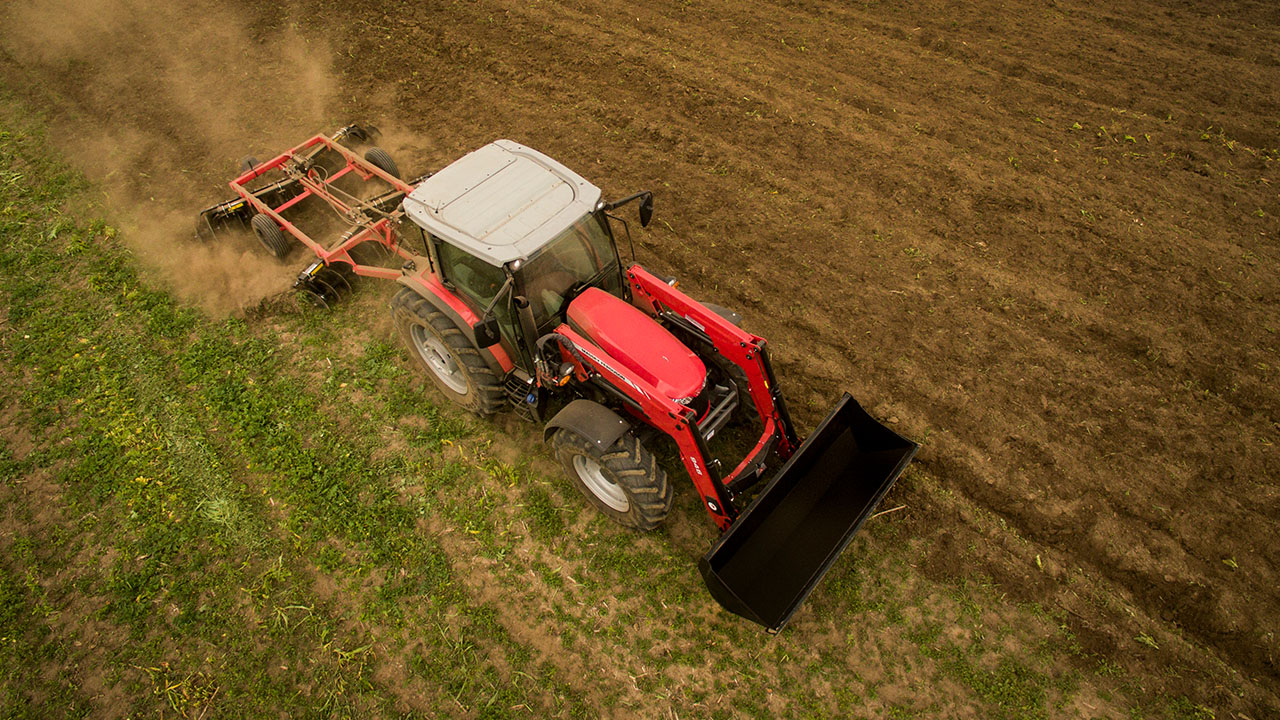 Massey Ferguson 6700 Series tractor with loader tilling a field from above, showcasing power and precision in ag work.