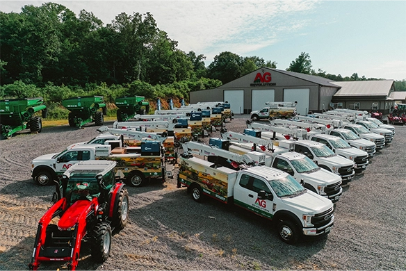 Fleet of AgRevolution branded service trucks and equipment parked in front of a dealership building, highlighting the company’s strong regional presence and mobile service capabilities.