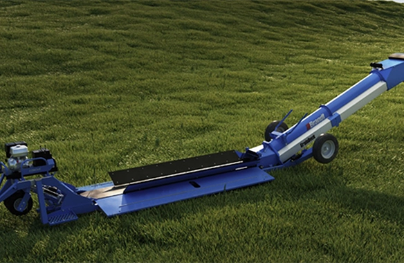 Brandt GrainDeck drive-over grain conveyor positioned on grass, designed for fast, low-profile unloading of grain trucks with efficient transfer to augers or bins.