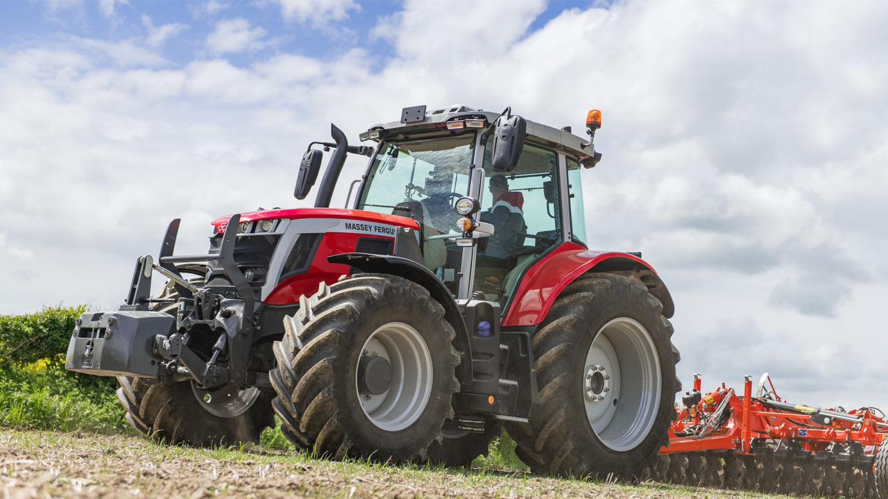 Massey Ferguson 6S Series tractor in the field, showcasing power and precision under a partly cloudy sky.