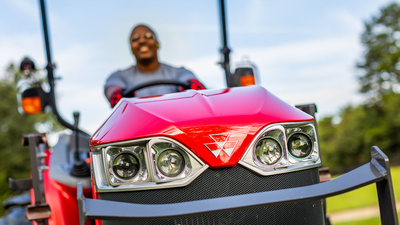 Close-up of Massey Ferguson 1800M Series tractor front grill and headlights with operator, showcasing bold design and brand identity.