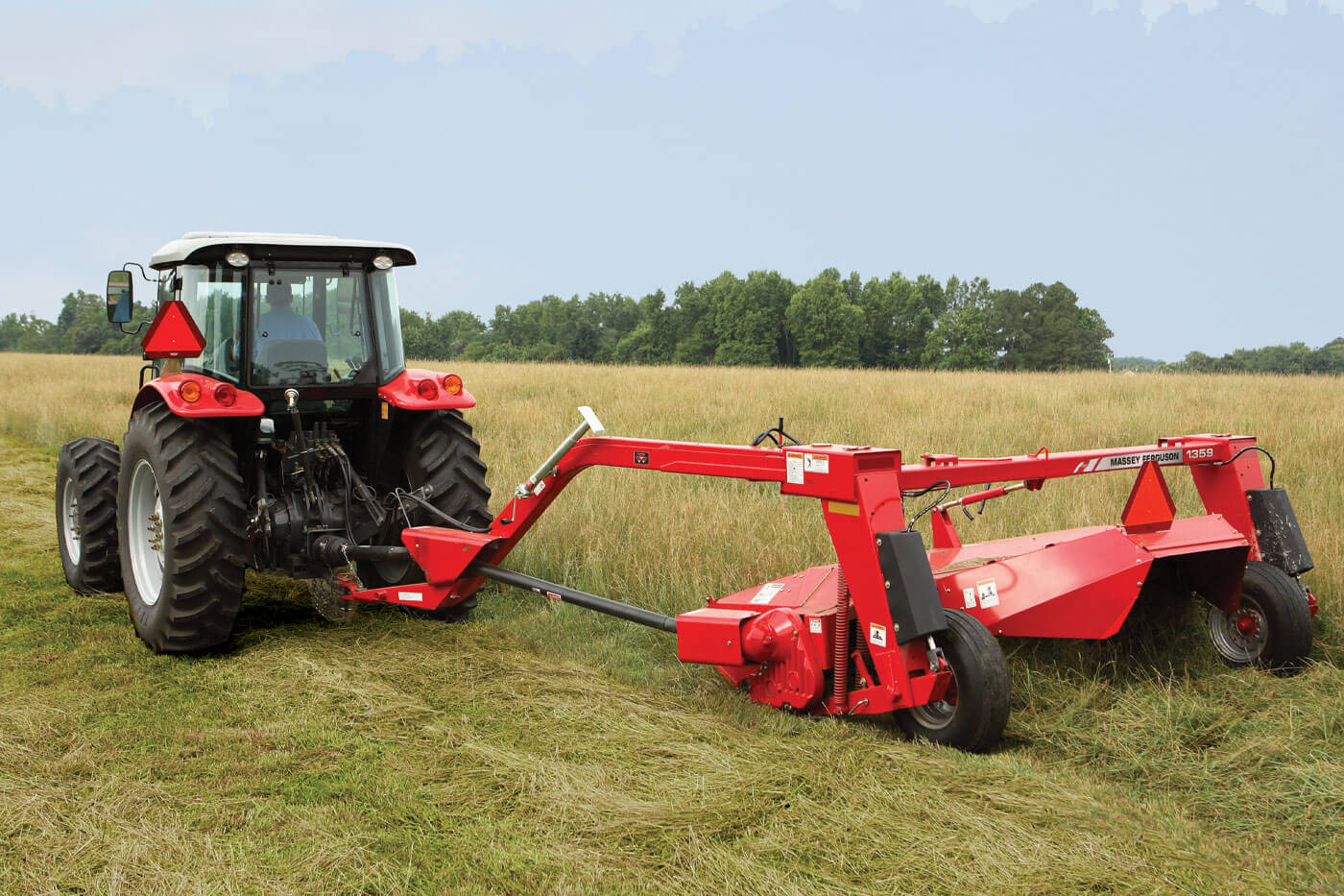 Massey Ferguson 1300 series mower conditioner cutting hay in open field, pulled by a MF tractor for efficient forage harvesting.