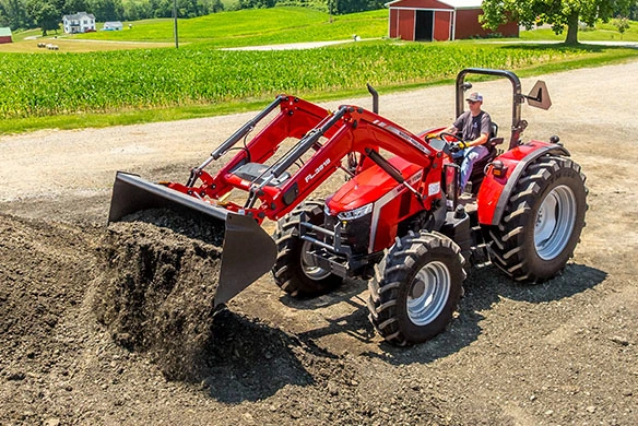 Massey Ferguson 5M open-station tractor using front loader to move and dump a bucket of dirt.