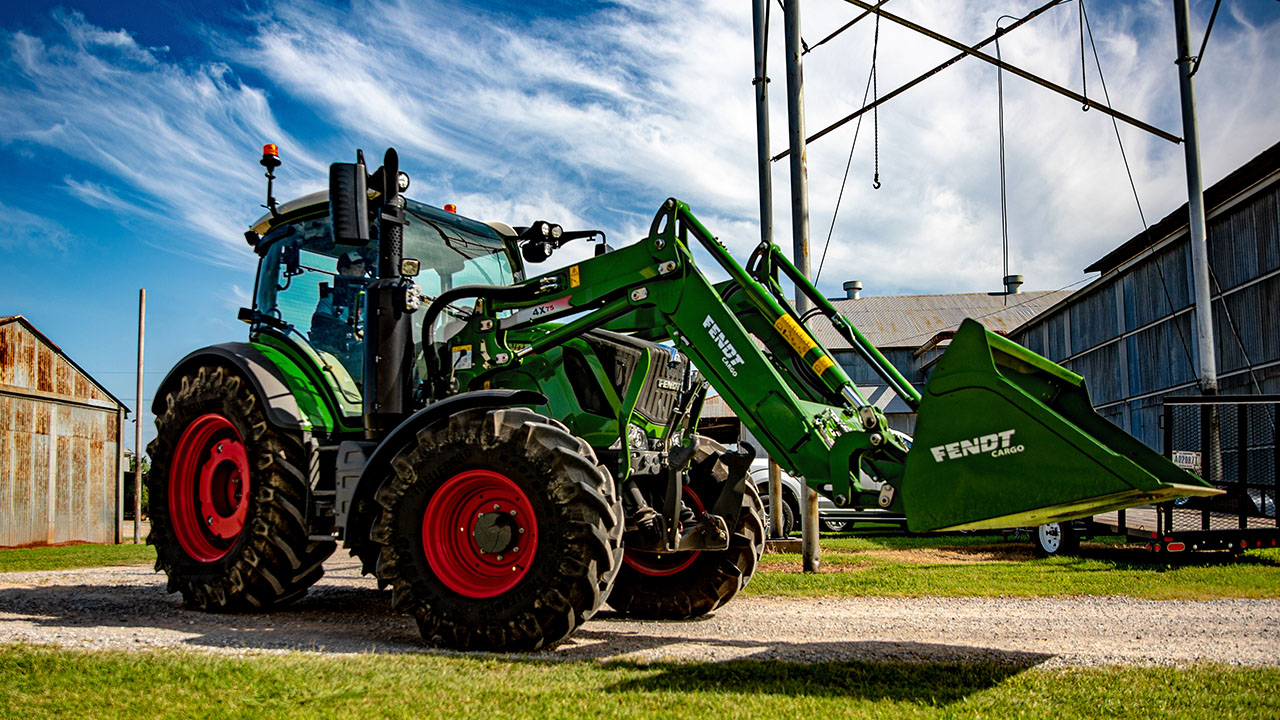 Fendt 300 Vario tractor with Fendt Cargo front loader parked on gravel near farm buildings, ready for versatile AGCO farm work.