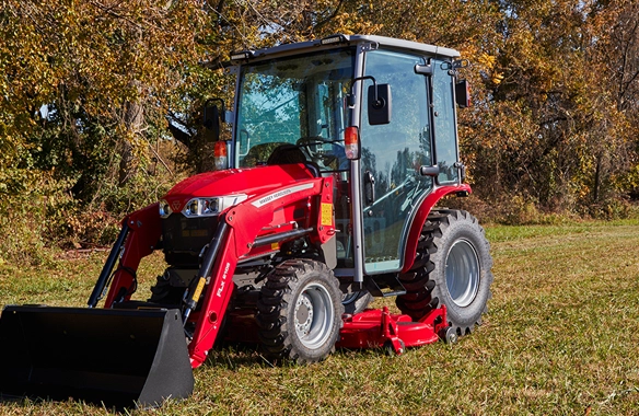 Massey Ferguson 1M Series compact tractor with cab and front loader parked on grassy terrain, ideal for year-round property maintenance.