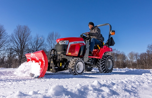 Massey Ferguson 1GC Series compact tractor clearing snow on a bright winter day.