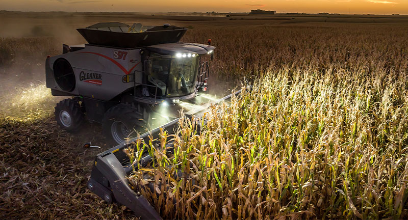 Thumbnail for Gleaner 3300 Command Series combine harvesting corn at dusk with LED lights, built for performance and late-day productivity.