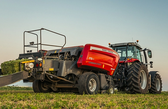 Rear angle of Massey Ferguson tractor with Hesston 1436 Series square baler in operation, producing high-density hay bales for commercial livestock and forage needs.