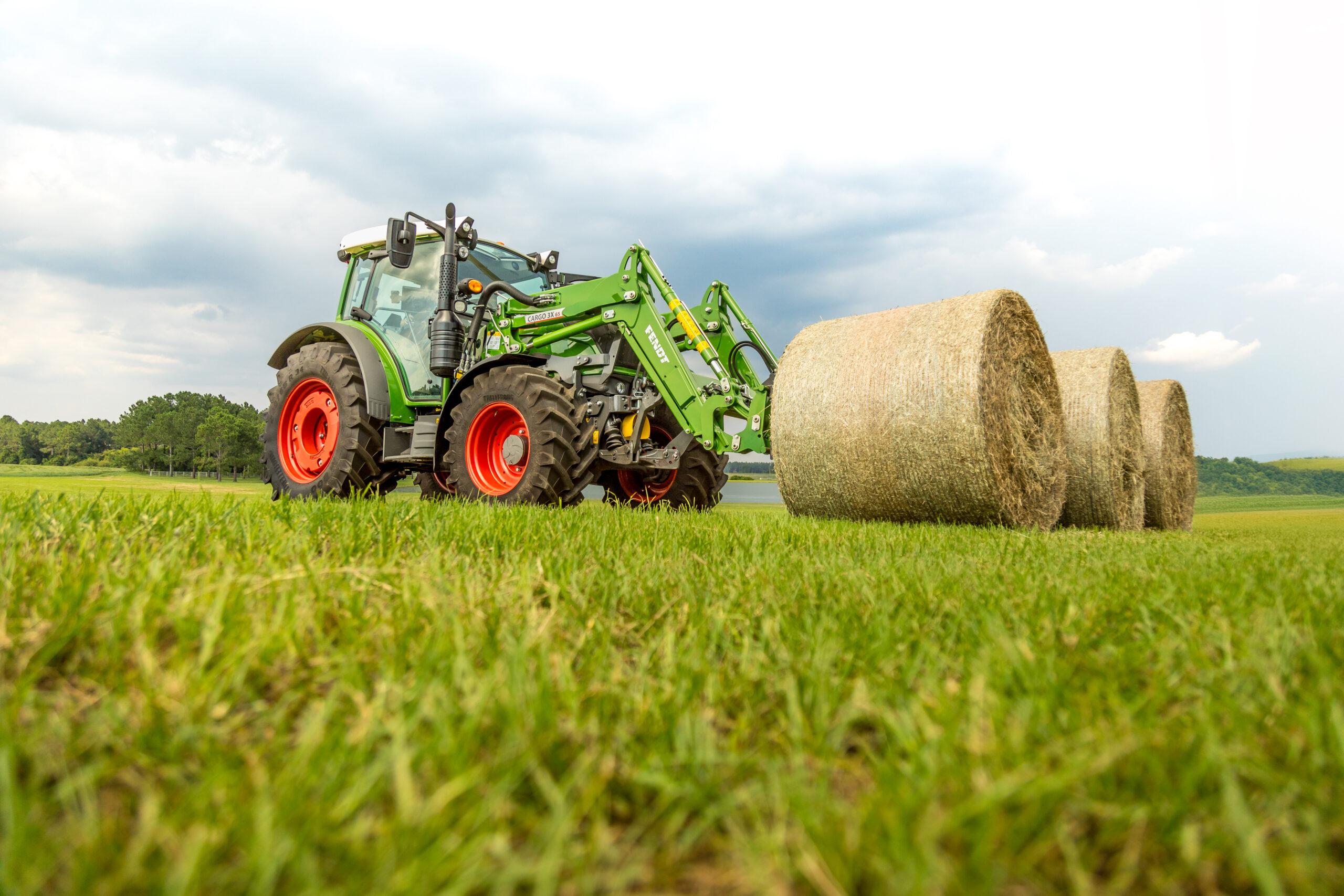 Fendt 200 Vario tractor with front loader lifting hay bale in field, ideal for livestock and forage operations.