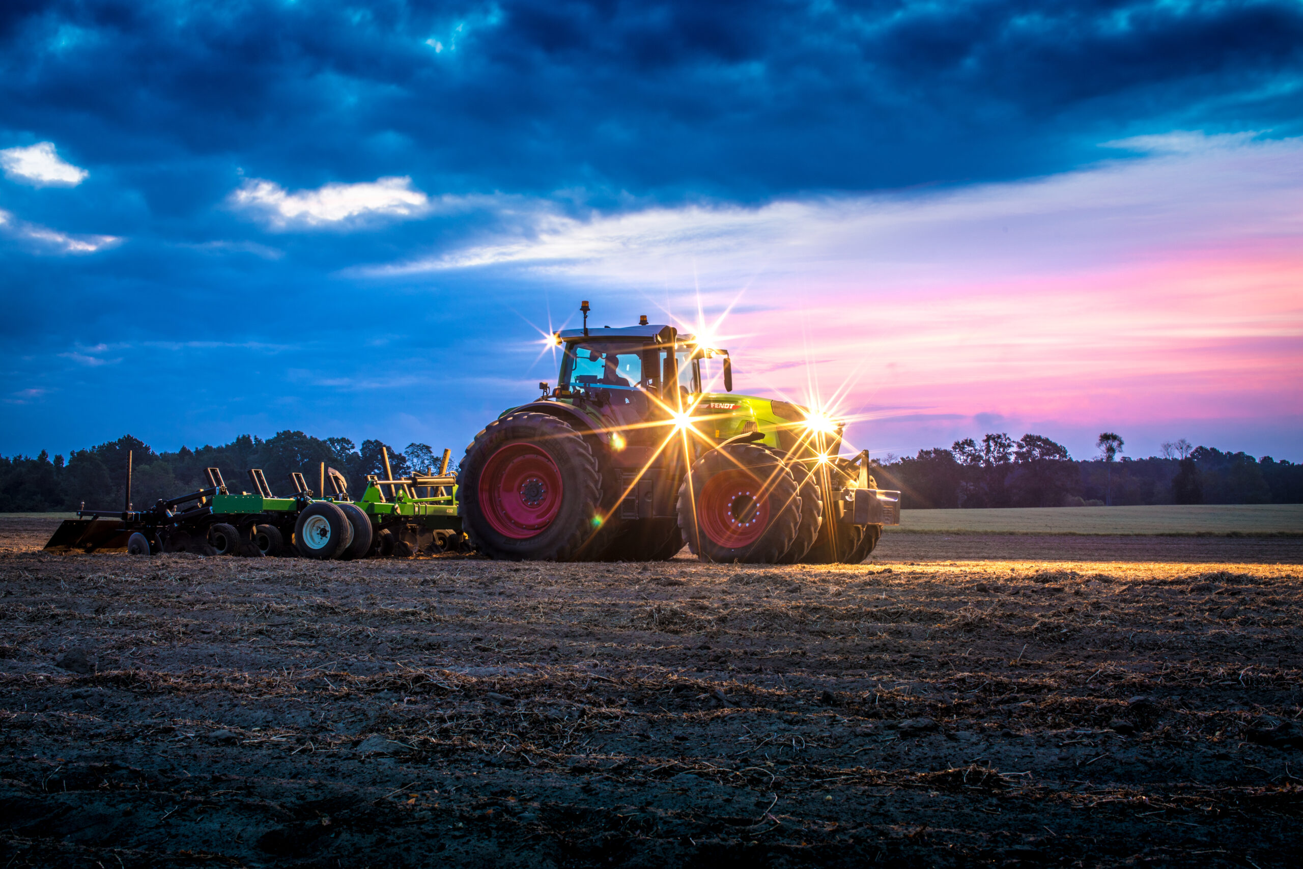 Fendt 900 Vario tractor working a field at dusk with implement, showcasing power, efficiency, and precision farming performance.