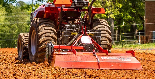 Woods equipment forward and reverse rotary tiller working a plot of land for garden soil prep.